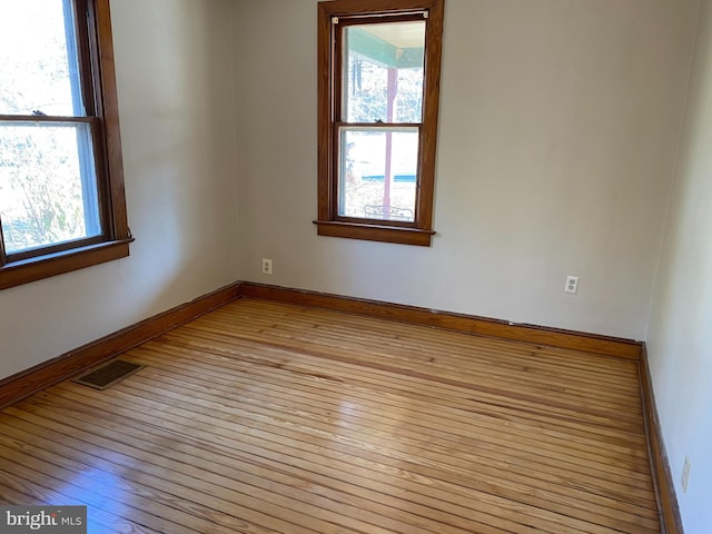 unfurnished room with light wood finished floors, baseboards, and visible vents