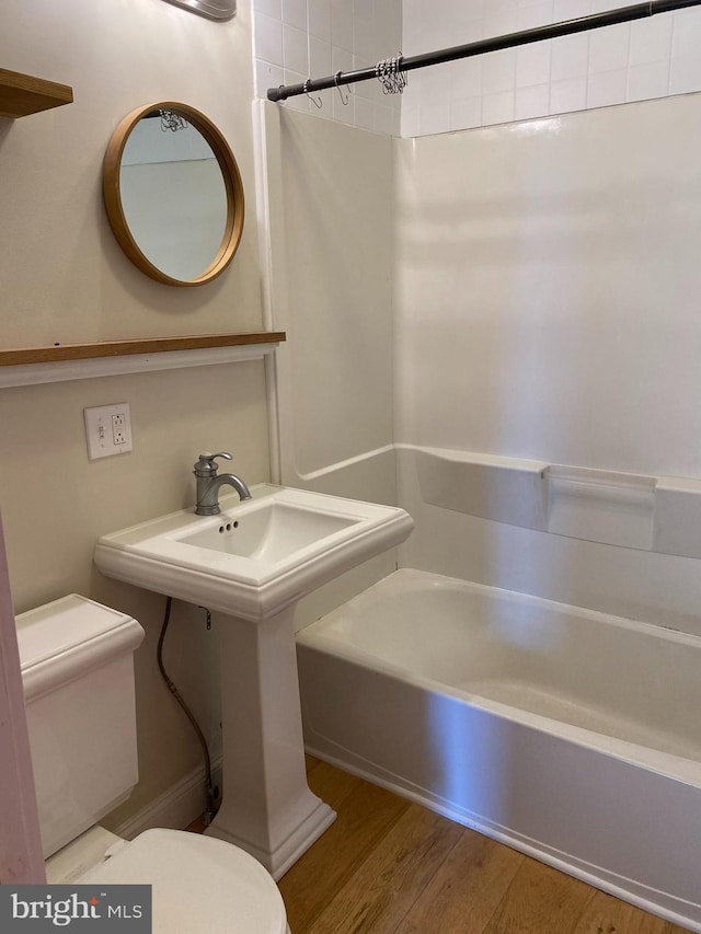 full bath featuring shower / tub combination, toilet, and wood finished floors