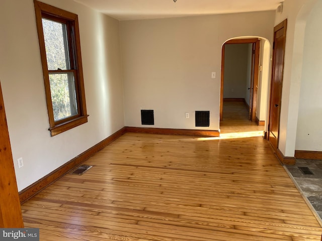 spare room featuring visible vents, arched walkways, and hardwood / wood-style floors