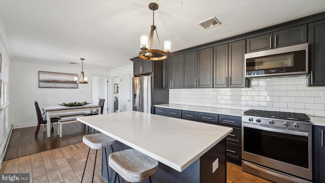 kitchen featuring visible vents, decorative backsplash, appliances with stainless steel finishes, an inviting chandelier, and crown molding