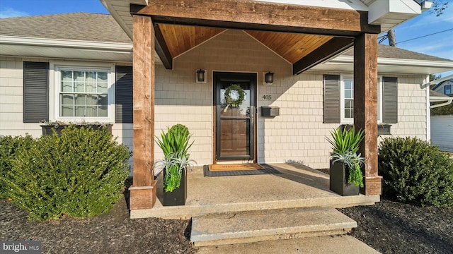 view of exterior entry featuring roof with shingles