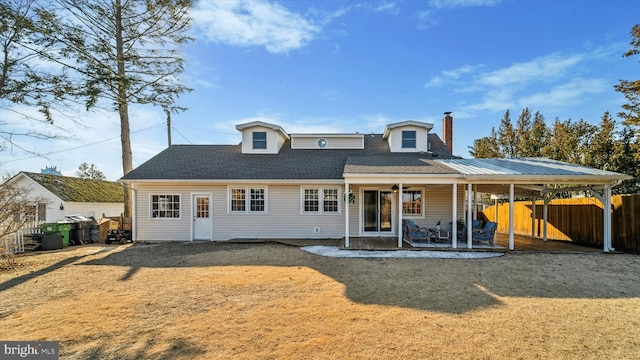 back of property featuring a patio, a chimney, an attached carport, roof with shingles, and fence