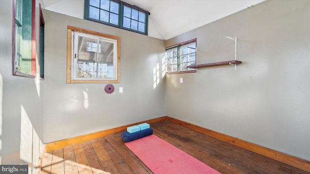 workout room featuring lofted ceiling, wood-type flooring, and baseboards