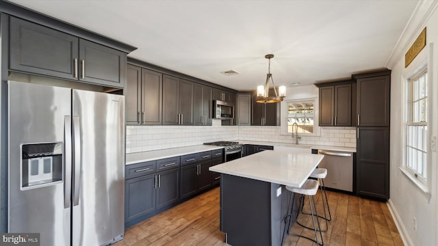 kitchen featuring appliances with stainless steel finishes, a breakfast bar area, light wood-type flooring, and a sink