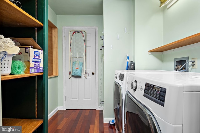 clothes washing area with dark wood-style flooring, laundry area, baseboards, and washing machine and clothes dryer