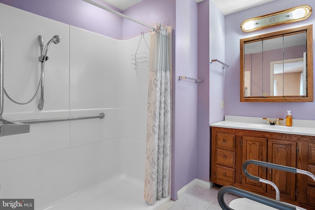 full bathroom with a shower stall, vanity, baseboards, and tile patterned floors