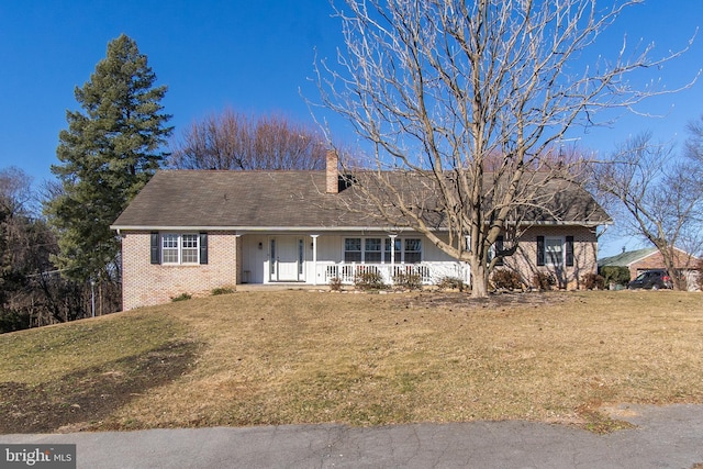 single story home with a chimney, a front lawn, a porch, and brick siding