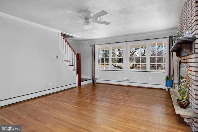 unfurnished living room with light wood-style floors, stairs, a baseboard heating unit, and crown molding