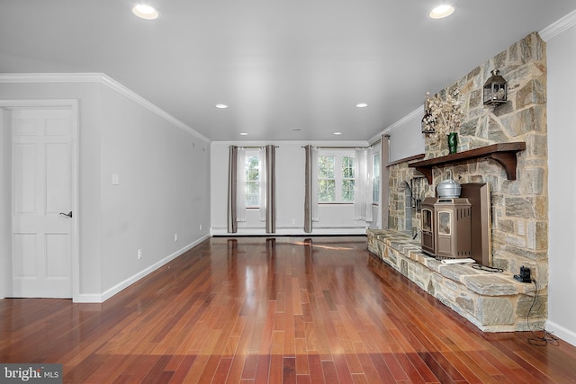 unfurnished living room with recessed lighting, wood finished floors, baseboards, ornamental molding, and a wood stove