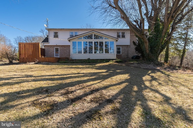 rear view of property featuring a yard, brick siding, and a sunroom