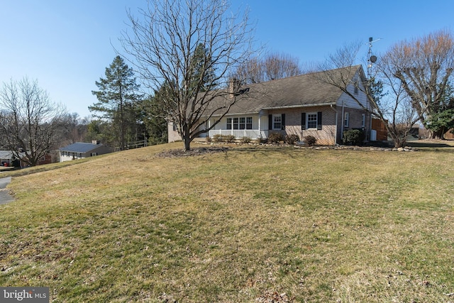 ranch-style home with brick siding, a chimney, and a front yard