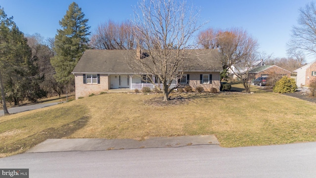 ranch-style house with covered porch, brick siding, and a front yard