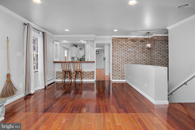 interior space with brick wall, wood finished floors, visible vents, ornamental molding, and baseboard heating