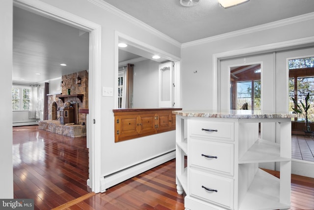 interior space with a baseboard radiator, wood-type flooring, ornamental molding, baseboard heating, and a fireplace