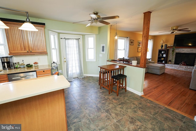 kitchen featuring open floor plan, stainless steel dishwasher, a fireplace, pendant lighting, and backsplash