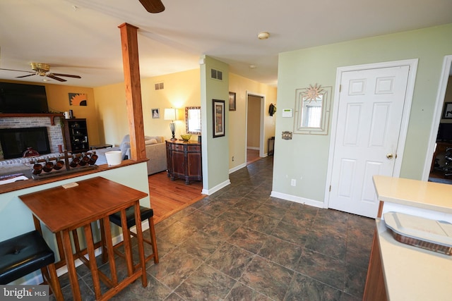 kitchen featuring a brick fireplace, visible vents, and a ceiling fan