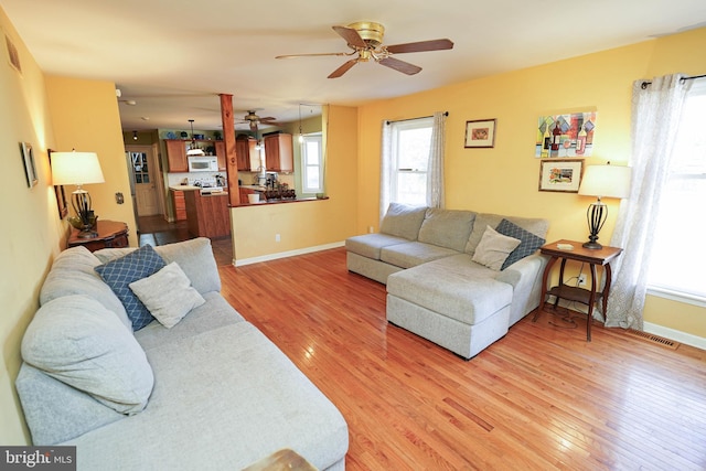 living room with baseboards, ceiling fan, visible vents, and light wood finished floors