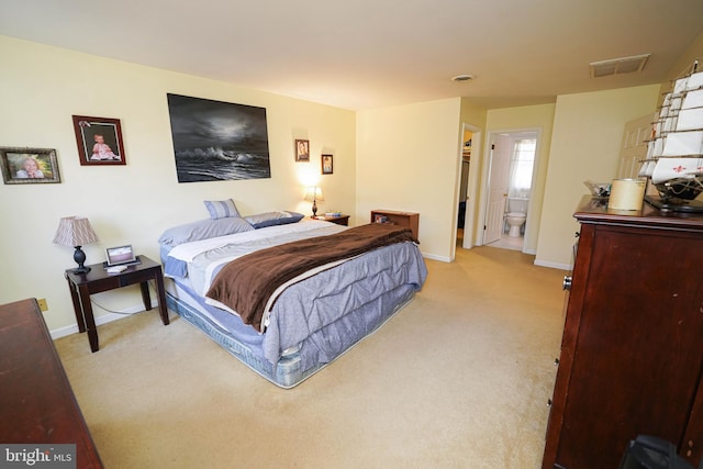 carpeted bedroom with baseboards, visible vents, and ensuite bathroom