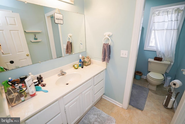 bathroom with toilet, tile patterned floors, vanity, and baseboards