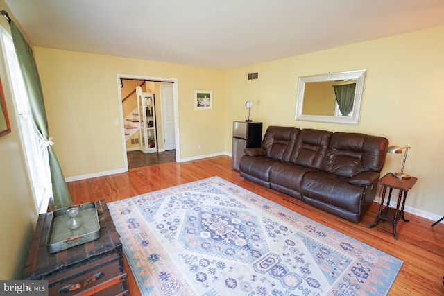 living room with visible vents, stairway, baseboards, and wood finished floors