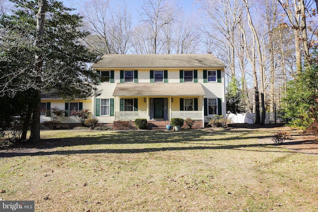 colonial-style house with covered porch, a front lawn, and fence