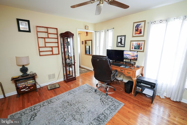 home office featuring wood-type flooring, visible vents, ceiling fan, and baseboards