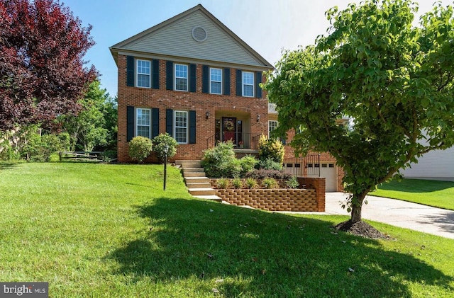 colonial inspired home with a garage, brick siding, concrete driveway, and a front yard