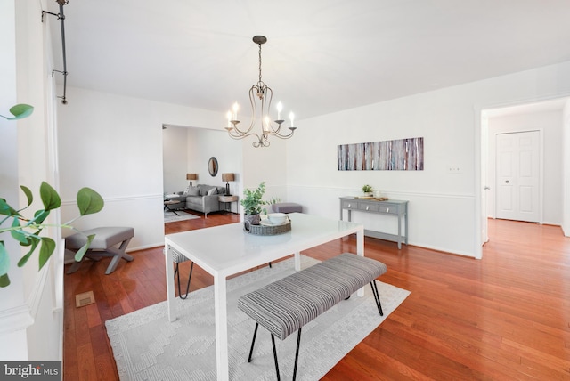 dining area with baseboards, an inviting chandelier, and wood finished floors