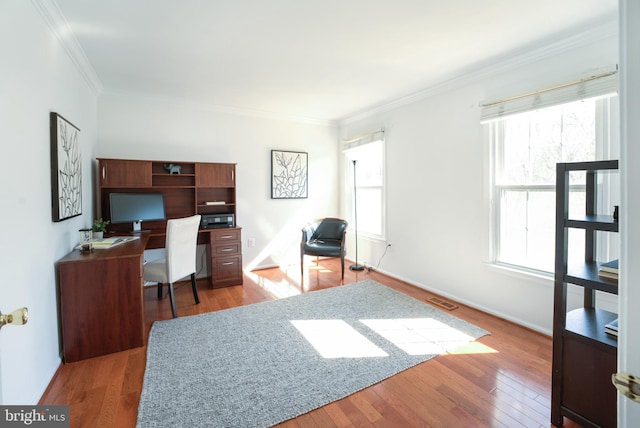 office space with visible vents, wood-type flooring, baseboards, and crown molding