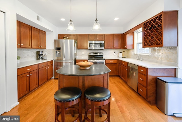 kitchen with light wood finished floors, visible vents, a kitchen island, a breakfast bar, and stainless steel appliances