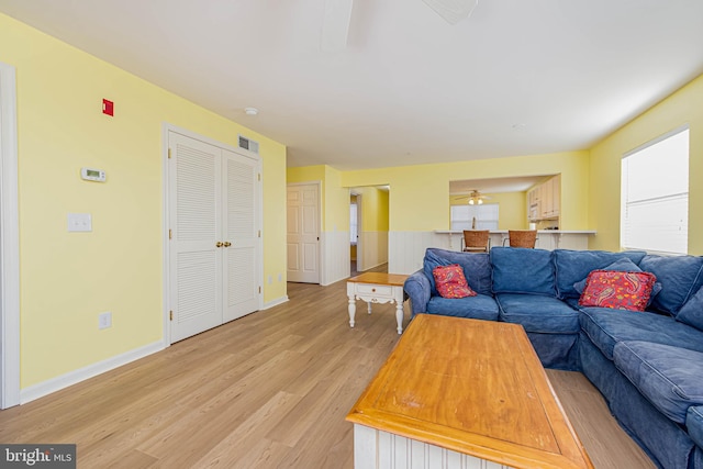 living area featuring a wainscoted wall, baseboards, visible vents, and light wood-type flooring