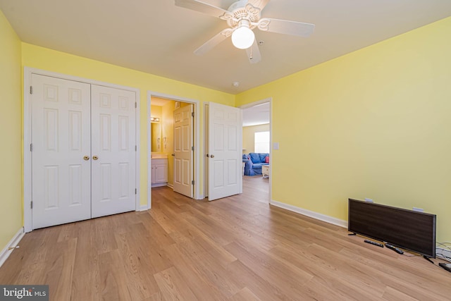 unfurnished bedroom featuring a closet, light wood-style flooring, a ceiling fan, and baseboards