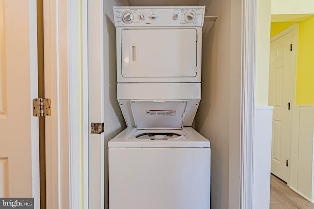 laundry room featuring light wood-type flooring, laundry area, and stacked washer / dryer