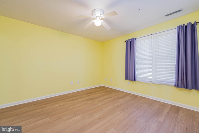 unfurnished room featuring ceiling fan, visible vents, baseboards, and wood finished floors