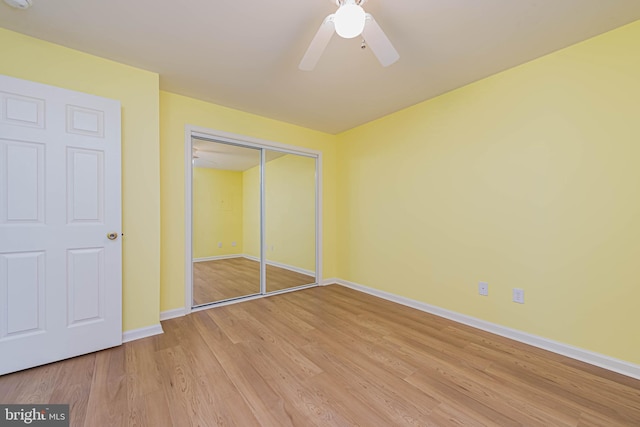 unfurnished bedroom featuring a closet, baseboards, light wood-style floors, and ceiling fan