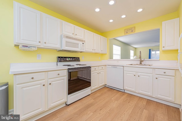 kitchen featuring a sink, white appliances, light wood-style flooring, and white cabinetry