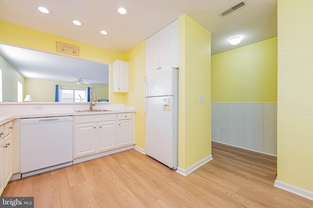 kitchen featuring white appliances, white cabinets, visible vents, and a sink