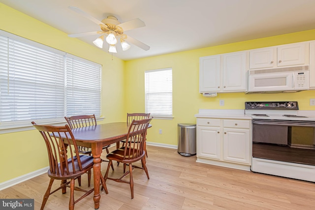 kitchen with baseboards, light countertops, light wood-style flooring, white cabinets, and white appliances