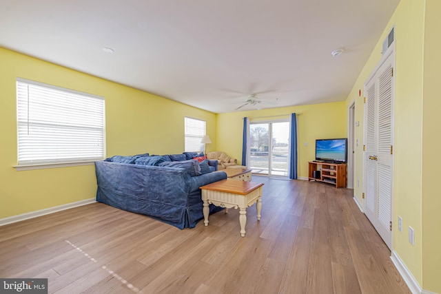 living area featuring ceiling fan, baseboards, and wood finished floors