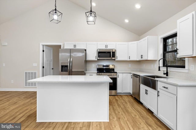 kitchen featuring a kitchen island, a sink, visible vents, light countertops, and appliances with stainless steel finishes