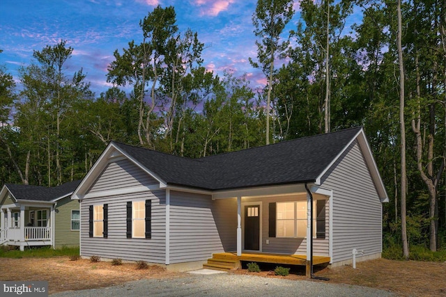 ranch-style home featuring covered porch and roof with shingles