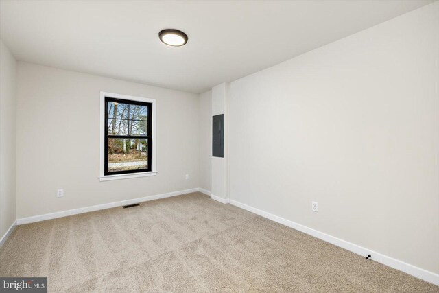 carpeted spare room featuring baseboards, electric panel, and visible vents