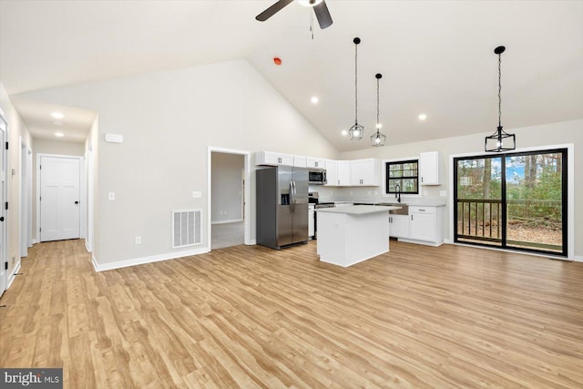 kitchen with stainless steel appliances, a kitchen island, visible vents, white cabinetry, and open floor plan