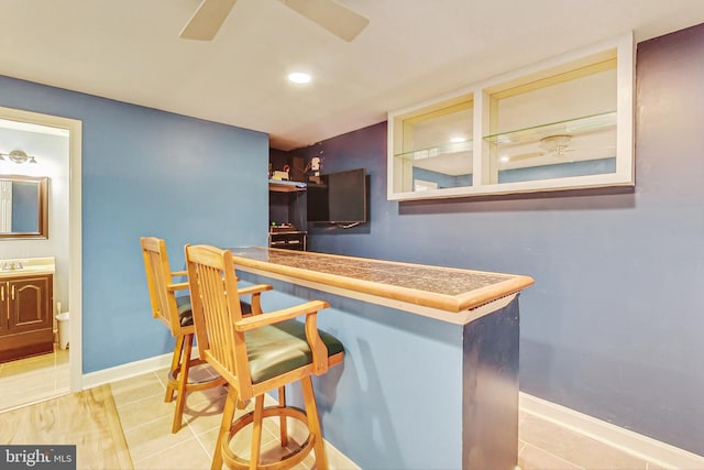 bar featuring a bar, baseboards, and tile patterned floors