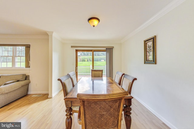 dining space with baseboards, crown molding, and light wood finished floors