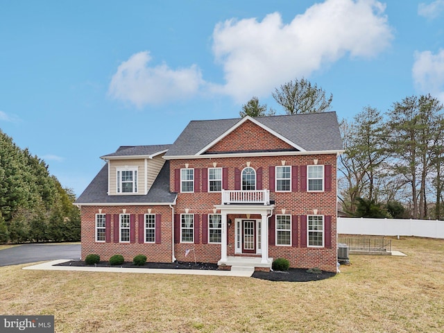 colonial house with central AC, a front lawn, fence, and brick siding