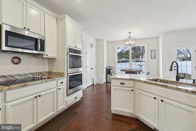 kitchen with light stone counters, a notable chandelier, stainless steel appliances, dark wood-type flooring, and a sink