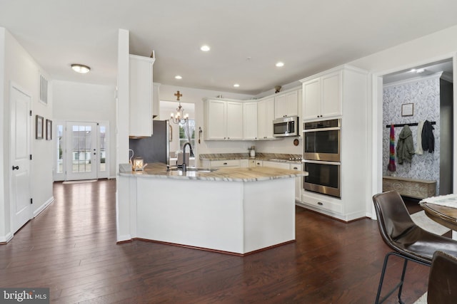 kitchen with dark wood finished floors, recessed lighting, appliances with stainless steel finishes, a sink, and a peninsula