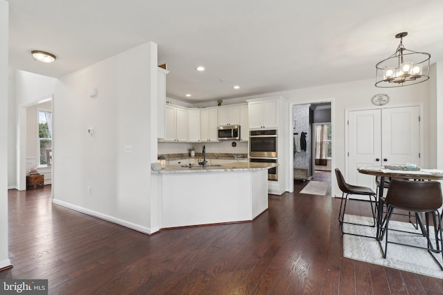 kitchen with white cabinets, appliances with stainless steel finishes, dark wood-style flooring, and a sink