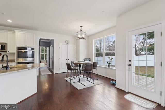 dining area featuring dark wood-type flooring, recessed lighting, a notable chandelier, and baseboards